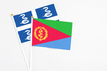 Eritrea and Martinique stick flags on white background. High quality fabric, miniature national flag. Peaceful global concept.White floor for copy space.
