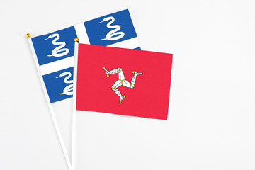 Isle Of Man and Martinique stick flags on white background. High quality fabric, miniature national flag. Peaceful global concept.White floor for copy space.