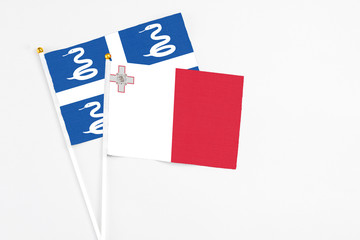 Malta and Martinique stick flags on white background. High quality fabric, miniature national flag. Peaceful global concept.White floor for copy space.