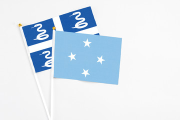 Micronesia and Martinique stick flags on white background. High quality fabric, miniature national flag. Peaceful global concept.White floor for copy space.