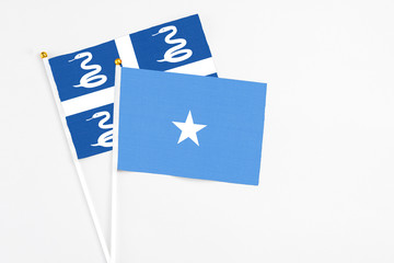 Somalia and Martinique stick flags on white background. High quality fabric, miniature national flag. Peaceful global concept.White floor for copy space.