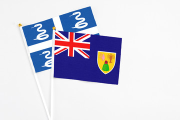 Fototapeta premium Turks And Caicos Islands and Martinique stick flags on white background. High quality fabric, miniature national flag. Peaceful global concept.White floor for copy space.
