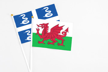 Wales and Martinique stick flags on white background. High quality fabric, miniature national flag. Peaceful global concept.White floor for copy space.