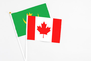 Canada and Mauritania stick flags on white background. High quality fabric, miniature national flag. Peaceful global concept.White floor for copy space.