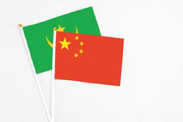 China and Mauritania stick flags on white background. High quality fabric, miniature national flag. Peaceful global concept.White floor for copy space.