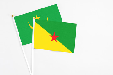 French Guiana and Mauritania stick flags on white background. High quality fabric, miniature national flag. Peaceful global concept.White floor for copy space.