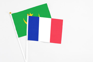 France and Mauritania stick flags on white background. High quality fabric, miniature national flag. Peaceful global concept.White floor for copy space.