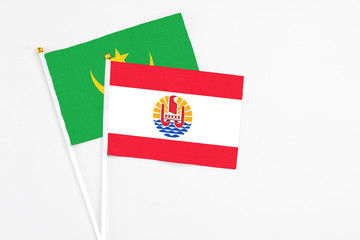 French Polynesia and Mauritania stick flags on white background. High quality fabric, miniature national flag. Peaceful global concept.White floor for copy space.