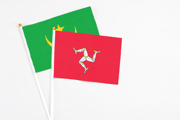 Isle Of Man and Mauritania stick flags on white background. High quality fabric, miniature national flag. Peaceful global concept.White floor for copy space.