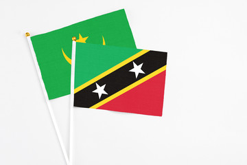 Saint Kitts And Nevis and Mauritania stick flags on white background. High quality fabric, miniature national flag. Peaceful global concept.White floor for copy space.