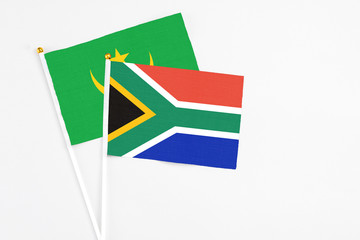 Obraz premium South Africa and Mauritania stick flags on white background. High quality fabric, miniature national flag. Peaceful global concept.White floor for copy space.