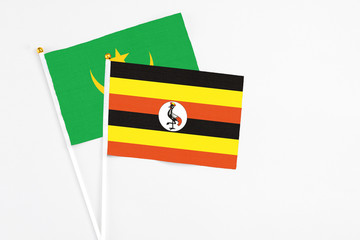 Uganda and Mauritania stick flags on white background. High quality fabric, miniature national flag. Peaceful global concept.White floor for copy space.