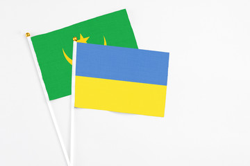 Ukraine and Mauritania stick flags on white background. High quality fabric, miniature national flag. Peaceful global concept.White floor for copy space.