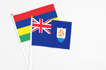 Fototapeta premium Anguilla and Mauritius stick flags on white background. High quality fabric, miniature national flag. Peaceful global concept.White floor for copy space.