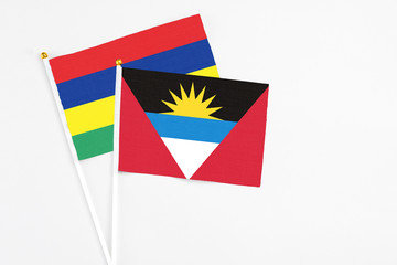 Antigua and Barbuda and Mauritius stick flags on white background. High quality fabric, miniature national flag. Peaceful global concept.White floor for copy space.