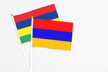 Armenia and Mauritius stick flags on white background. High quality fabric, miniature national flag. Peaceful global concept.White floor for copy space.