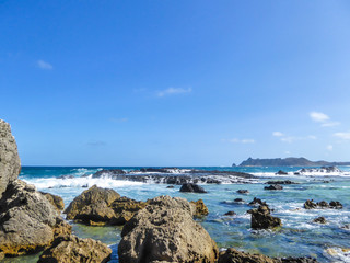 An idyllic beach in Lombok, Pantai Nambung in Indonesia. The beach is stony, with many rock formations emerging from the water. Water has many shades of blue. Perfect day for relaxation on the beach