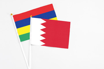 Bahrain and Mauritius stick flags on white background. High quality fabric, miniature national flag. Peaceful global concept.White floor for copy space.