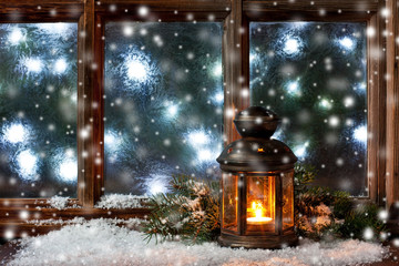 Winter  frost window with burning lantern, Christmas  or Advent time