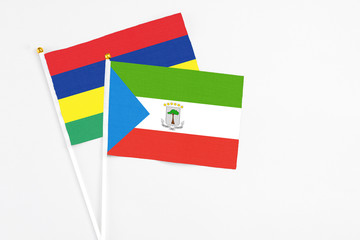 Equatorial Guinea and Mauritius stick flags on white background. High quality fabric, miniature national flag. Peaceful global concept.White floor for copy space.