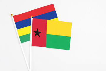 Guinea Bissau and Mauritius stick flags on white background. High quality fabric, miniature national flag. Peaceful global concept.White floor for copy space.