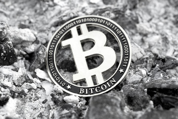 Cryptocurrency monochrome bitcoin token among ashes. Loss of capital. Close up.