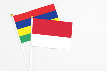 Monaco and Mauritius stick flags on white background. High quality fabric, miniature national flag. Peaceful global concept.White floor for copy space.
