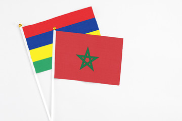 Morocco and Mauritius stick flags on white background. High quality fabric, miniature national flag. Peaceful global concept.White floor for copy space.