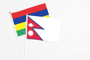 Nepal and Mauritius stick flags on white background. High quality fabric, miniature national flag. Peaceful global concept.White floor for copy space.