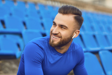 A guy in sportswear is sitting in the stadium after training.