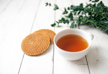 Cup of tea with German caramel waffles on white wooden table