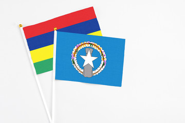Northern Mariana Islands and Mauritius stick flags on white background. High quality fabric, miniature national flag. Peaceful global concept.White floor for copy space.