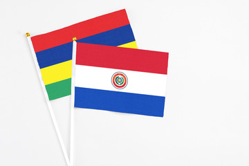 Paraguay and Mauritius stick flags on white background. High quality fabric, miniature national flag. Peaceful global concept.White floor for copy space.