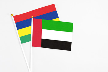 United Arab Emirates and Mauritius stick flags on white background. High quality fabric, miniature national flag. Peaceful global concept.White floor for copy space.