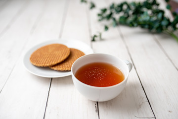 Cup of tea with German caramel waffles on white wooden table