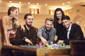Cheerful group of friends enjoys winning poker roulette in a casino.