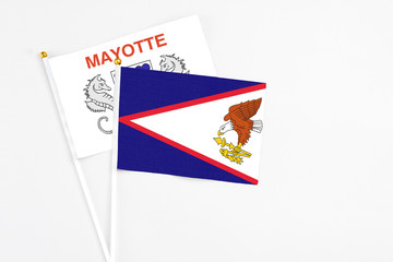 American Samoa and Mayotte stick flags on white background. High quality fabric, miniature national flag. Peaceful global concept.White floor for copy space.