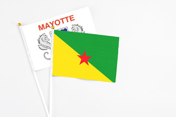 French Guiana and Mayotte stick flags on white background. High quality fabric, miniature national flag. Peaceful global concept.White floor for copy space.