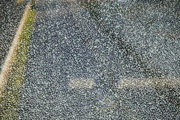 Broken glass, cracked box or shockproof fencing at fence on the road. Texture or background. Vandalism, safety glass production or Broken glass at sunset. hole in the glass, a prank or an accident
