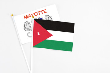 Jordan and Mayotte stick flags on white background. High quality fabric, miniature national flag. Peaceful global concept.White floor for copy space.