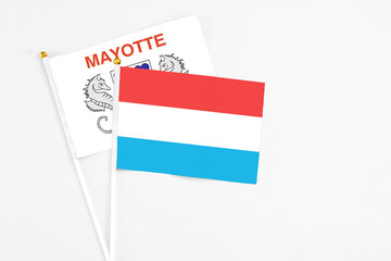 Luxembourg and Mayotte stick flags on white background. High quality fabric, miniature national flag. Peaceful global concept.White floor for copy space.