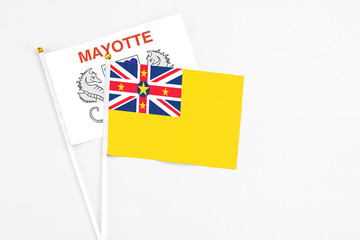 Niue and Mayotte stick flags on white background. High quality fabric, miniature national flag. Peaceful global concept.White floor for copy space.