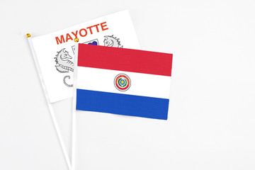 Paraguay and Mayotte stick flags on white background. High quality fabric, miniature national flag. Peaceful global concept.White floor for copy space.