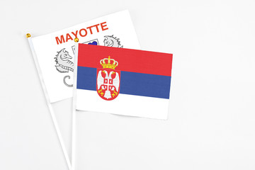 Serbia and Mayotte stick flags on white background. High quality fabric, miniature national flag. Peaceful global concept.White floor for copy space.