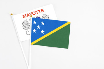 Solomon Islands and Mayotte stick flags on white background. High quality fabric, miniature national flag. Peaceful global concept.White floor for copy space.