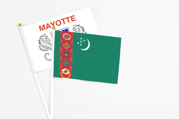 Turkmenistan and Mayotte stick flags on white background. High quality fabric, miniature national flag. Peaceful global concept.White floor for copy space.