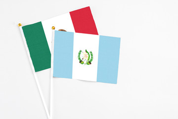 Guatemala and Mexico stick flags on white background. High quality fabric, miniature national flag. Peaceful global concept.White floor for copy space.
