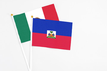 Haiti and Mexico stick flags on white background. High quality fabric, miniature national flag. Peaceful global concept.White floor for copy space.