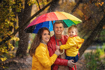 happy family walking under the rain at autumn park