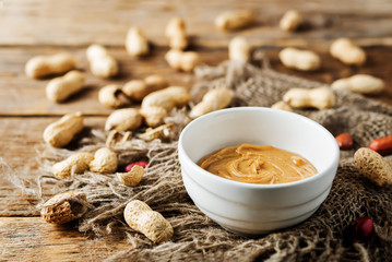 Peanut butter with peanuts on a dark wood background